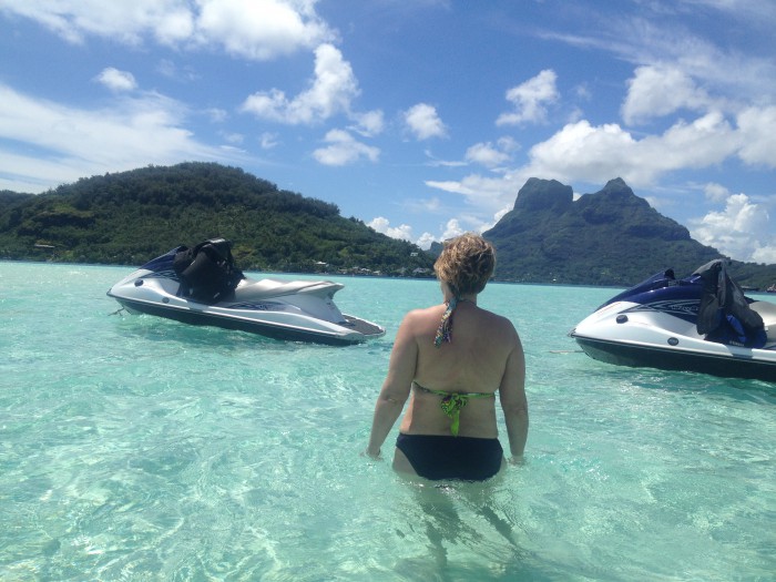 woman in ocean next to two jet skis