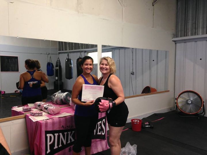 Two women holding a certificate and wearing boxing mitts at Pink Gloves Boxing Gym