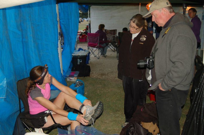 Trail runner at the aid station talks with support crew.