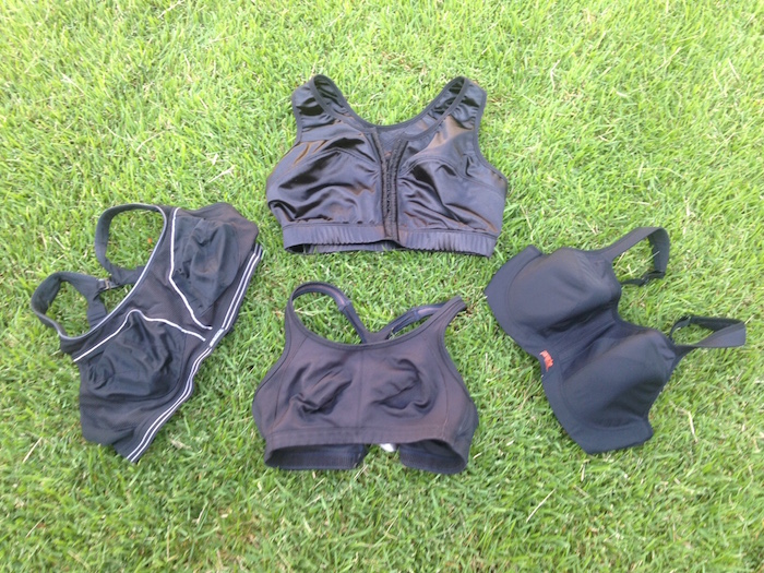 Four black running bras arranged on grass.