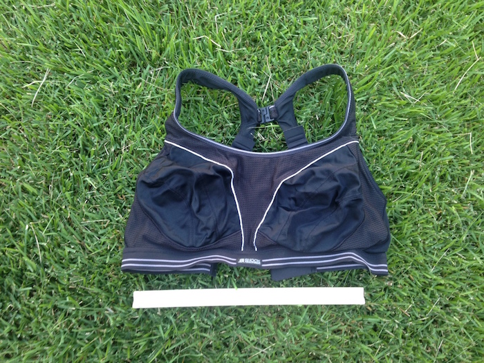 Black running bra on grass with ruler for scale.
