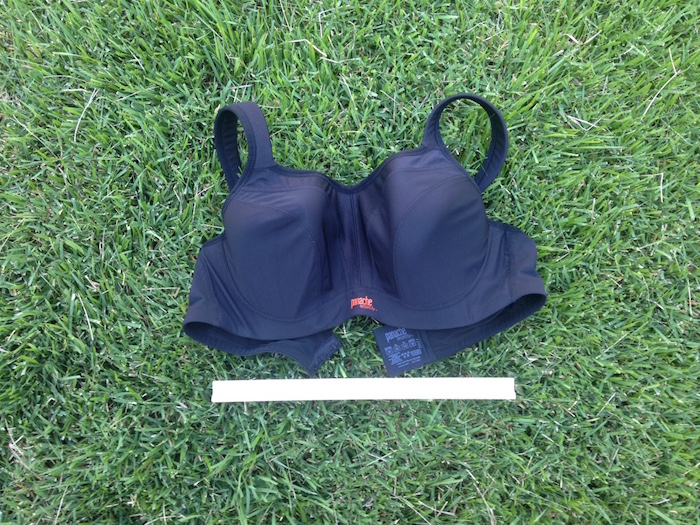 Padded cup running bra on grass with ruler for scale.