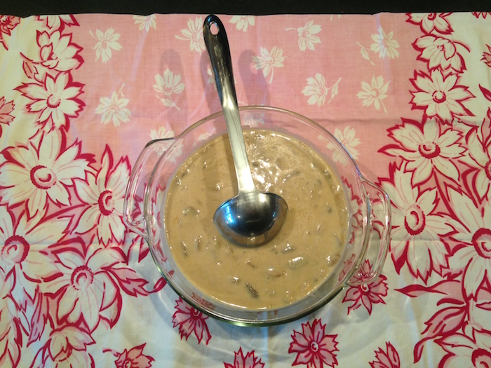 Photo of bowl of homemade cream of mushroom soup on pink flowered table cloth.