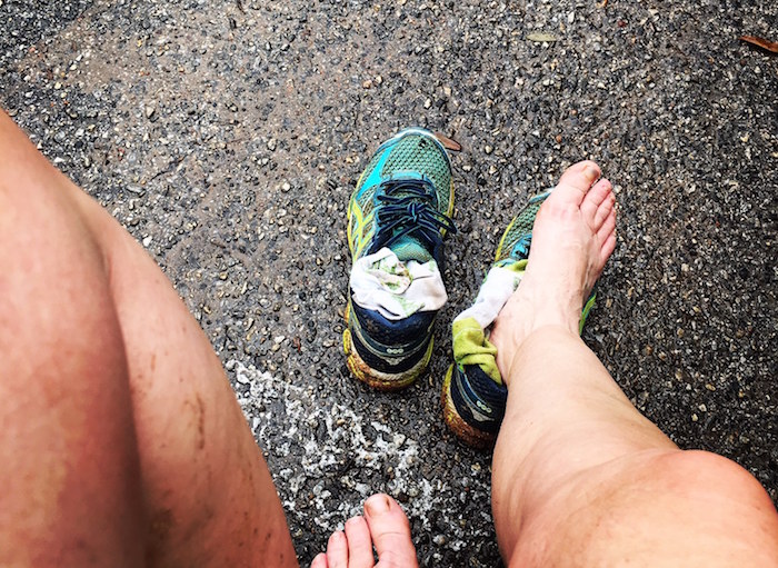 Photo of runner's dirty legs and feet after taking off shoes.