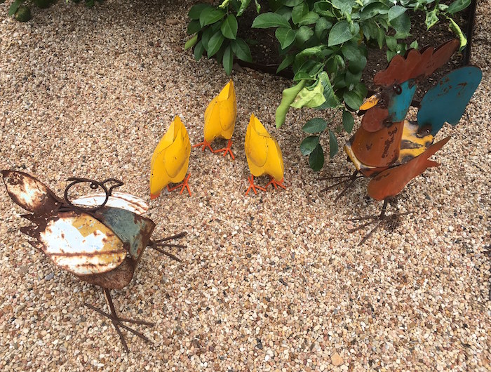 Hen, rooster, and three yellow chickens in metal yard art.
